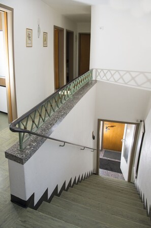 Un escalier avec une rampe et un sol à motifs menant à une porte.