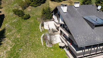 Ein modernes, zweistöckiges Haus mit geneigtem Dach, einer sichtbaren Satellitenschüssel und einer gepflasterten Terrasse.