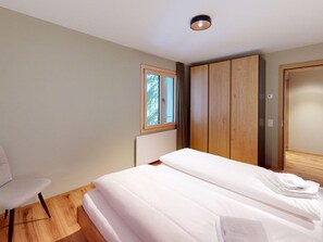A modern bedroom with a bed, a chair, and a wardrobe. - 1510 Chesa Barlangia Briza by Interhome (Valbella)