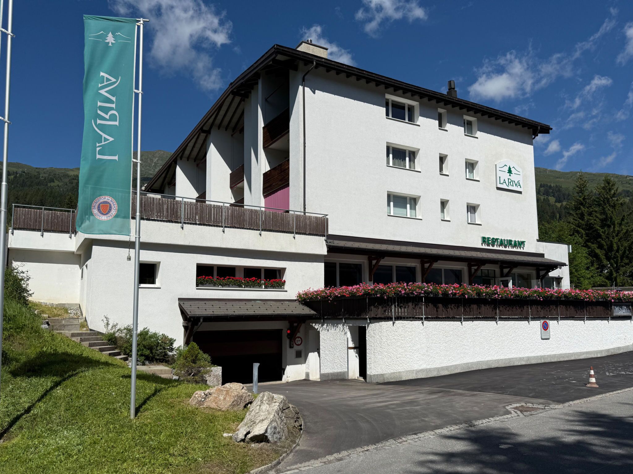 Un edificio con letrero de restaurante, una bandera y vistas a las montañas.