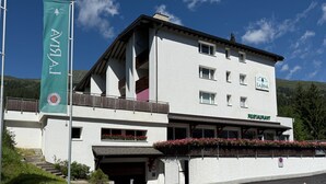 Um edifício com um letreiro de restaurante, uma bandeira e vista para as montanhas.