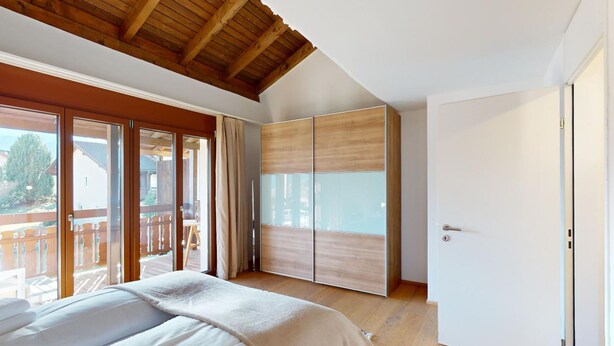Ein Schlafzimmer mit einem großen Bett, Schiebetüren und Blick ins Freie.