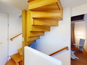 A wooden spiral staircase with a white handrail and a blue accent wall. - 1905 Tgampi Sot Lantsch/Lenz by Interhome (Lantsch)