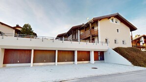Ein mehrstöckiges Gebäude mit flachem Dach, einem Balkon und einer Garageneinfahrt.