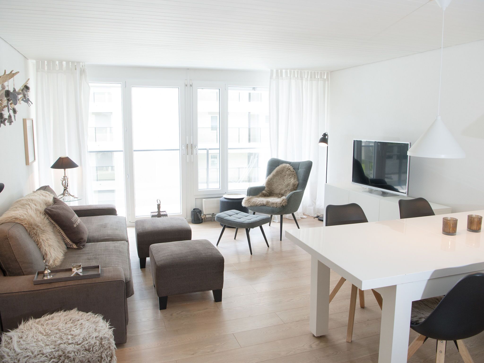 Una sala moderna con un sofá, un reposapiés, un sillón y una mesa de comedor.