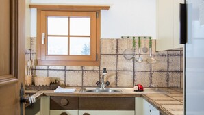 Een compacte keuken met een raam, een spoelbak en een betegelde spatwand.