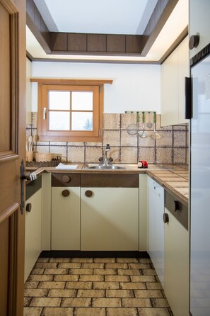A compact kitchen with a window, a sink, and a tiled backsplash. - 1615 Bot La Pala by Interhome (Lenzerheide)