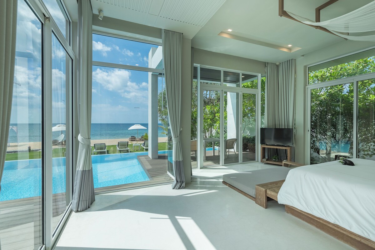 Quarto moderno com uma cama grande, televisão e vista para o mar.