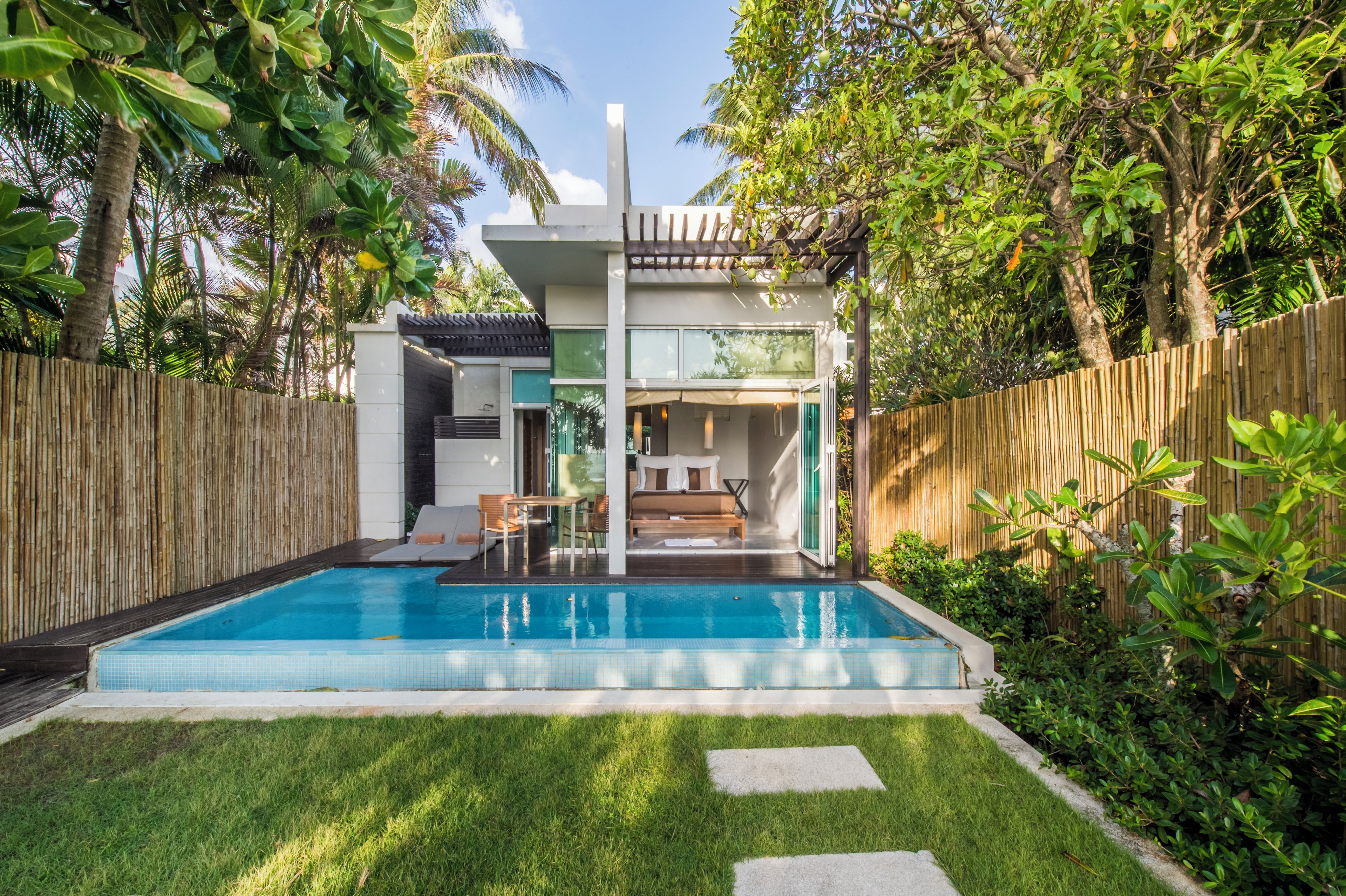 A modern house with a swimming pool, a patio with outdoor furniture, and a wooden fence.