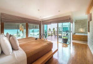 Quarto moderno com uma cama grande, uma varanda com vista para o oceano e uma área de spa com banheira.