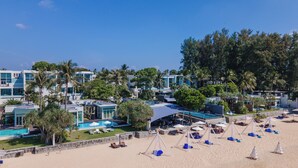 A resort with multiple buildings, a swimming pool, and beach areas with umbrellas and lounge chairs. - Aleenta Phuket - Phang Nga Resort and Spa (Takua Thung)
