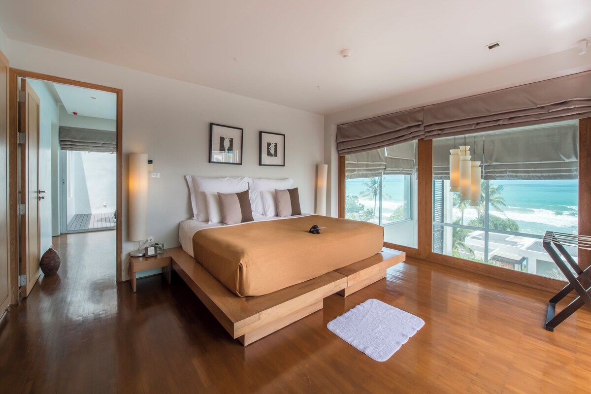 Un dormitorio amplio con una cama grande, vistas al océano y un balcón.