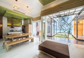A modern kitchen with a dining area and a large window overlooking a garden. - Aleenta Phuket - Phang Nga Resort and Spa (Takua Thung)