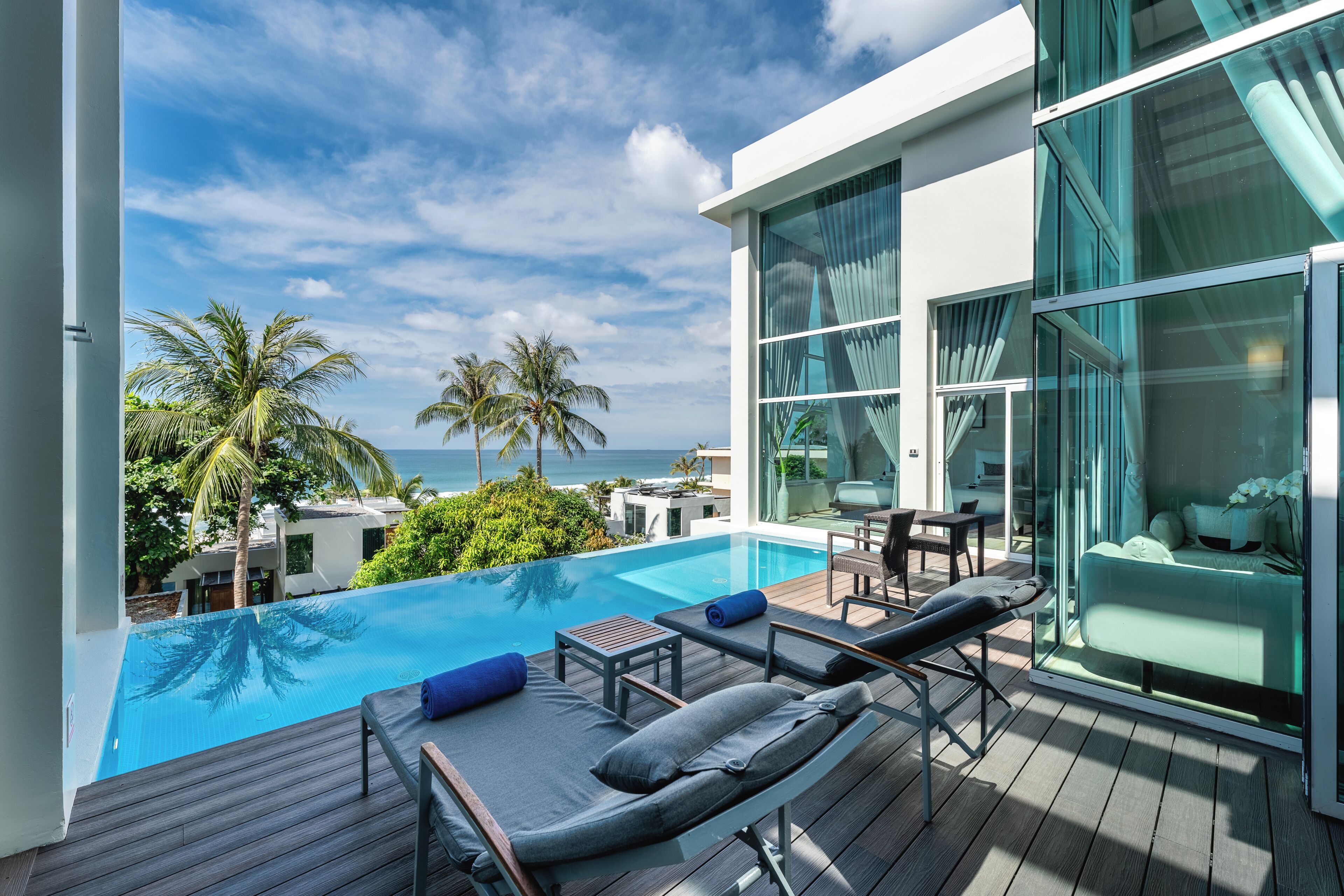 Ein modernes Hotel mit Pool, Liegestühlen und Meerblick.