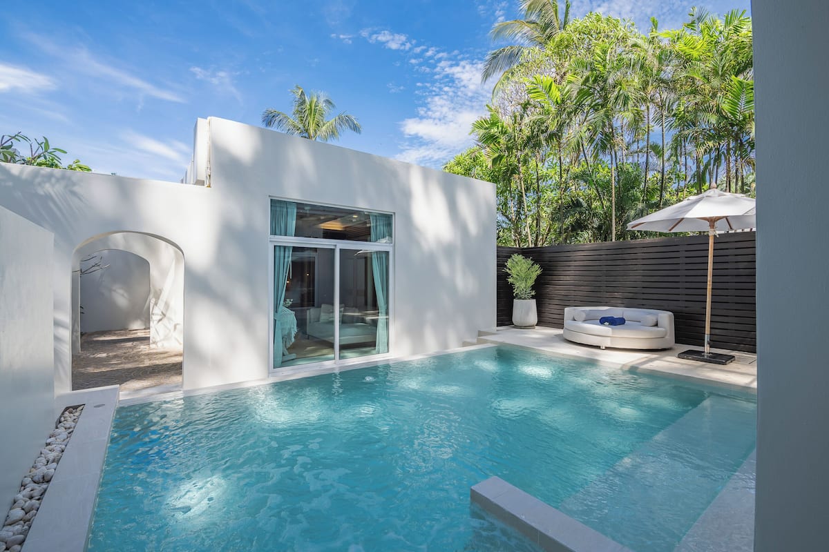 A modern pool area with a clear view of the pool, a seating area with a lounge chair, and a wooden fence.