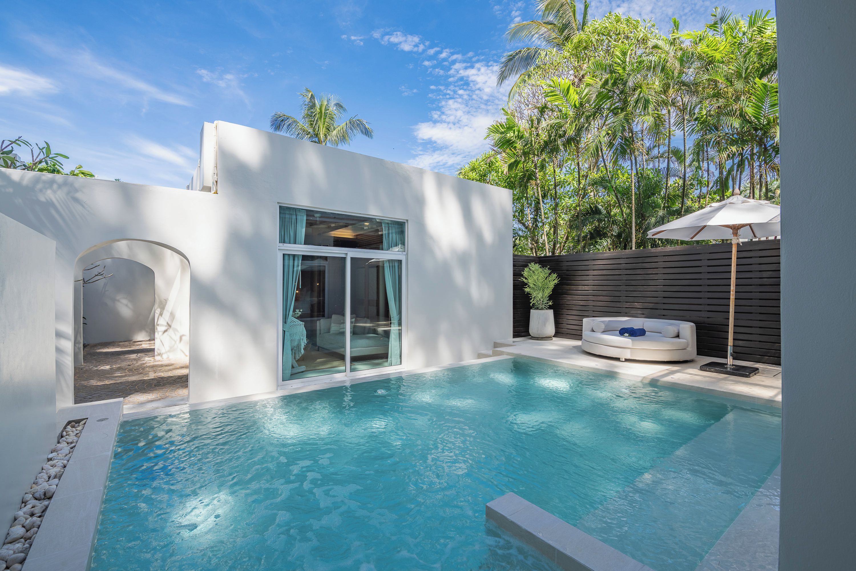 A modern pool area with a clear view of the pool, a seating area with a lounge chair, and a wooden fence.
