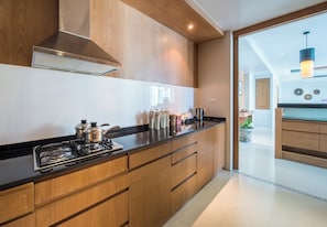 A modern kitchen with wooden cabinets, a stainless steel stove, and a black countertop. - Aleenta Phuket - Phang Nga Resort and Spa (Takua Thung)