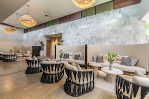 A modern lounge area with seating arrangements, marble walls, and hanging pendant lights. - Aleenta Phuket - Phang Nga Resort and Spa (Takua Thung)