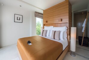 Ein modernes Hotelzimmer mit einem großen Bett, einem Holzkopfteil, einem gerahmten Bild an der Wand und einem großen Fenster.