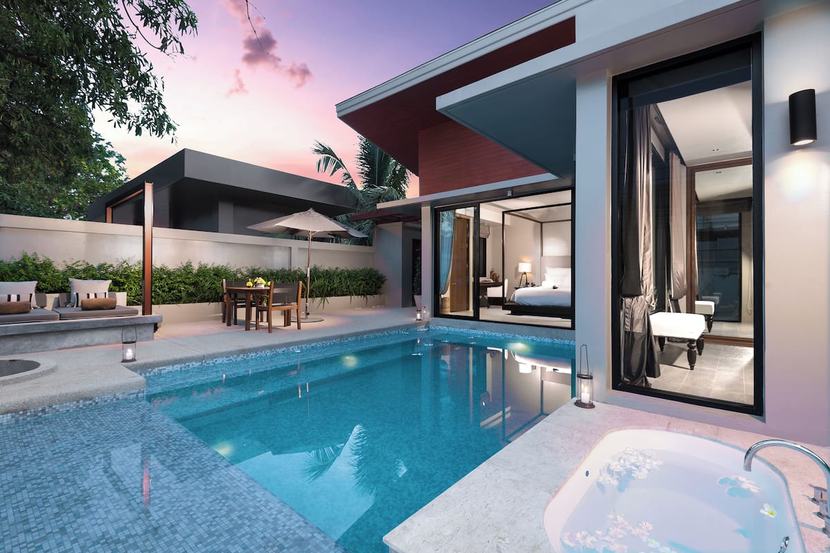 A modern pool area with a clear pool, a hot tub, and a glass-enclosed bedroom.