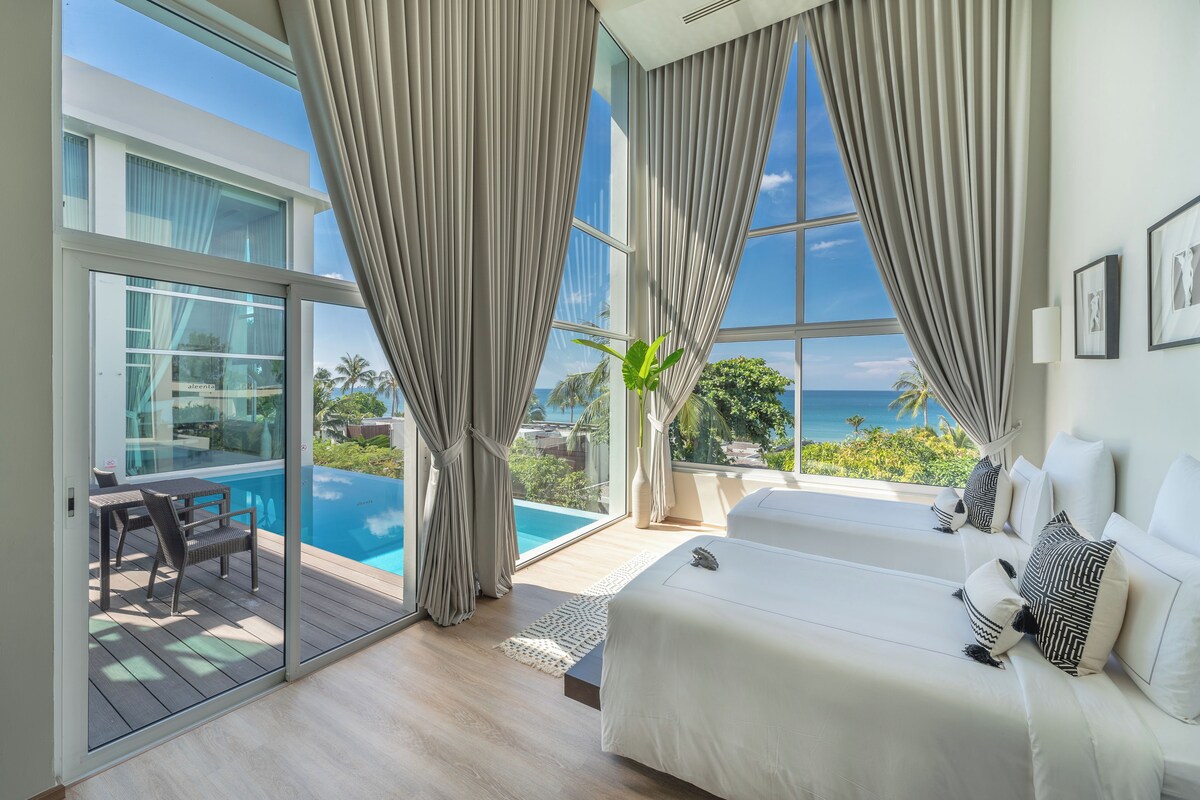 Quarto com cama grande, vista para o oceano e varanda com piscina.