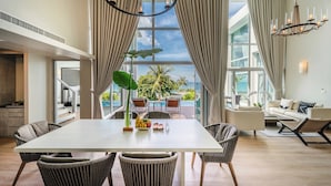 A spacious living area with a dining table, chairs, a sofa, and a view of the ocean. - Aleenta Phuket - Phang Nga Resort and Spa (Takua Thung)