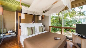 A bedroom with a large bed, a TV, and a view of greenery outside.
