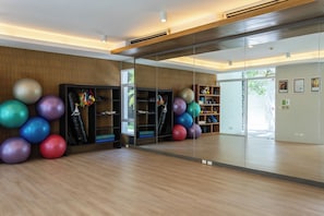 Ett gym med träningsbollar, en boxningssäck och en vägg med speglar.