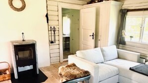 Un salon chaleureux avec un canapé blanc, une petite table, une cheminée et une fenêtre avec des rideaux.