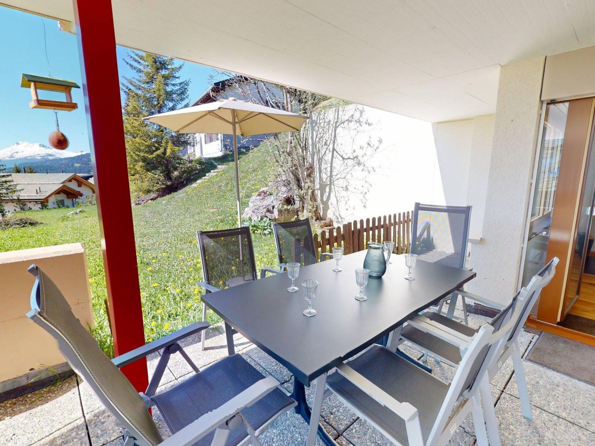 An outdoor dining area with a table, chairs, and a hanging light fixture.