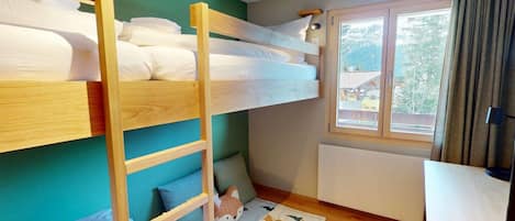 Habitación con literas, un escritorio, una ventana con vistas y una alfombra con estampado animal.