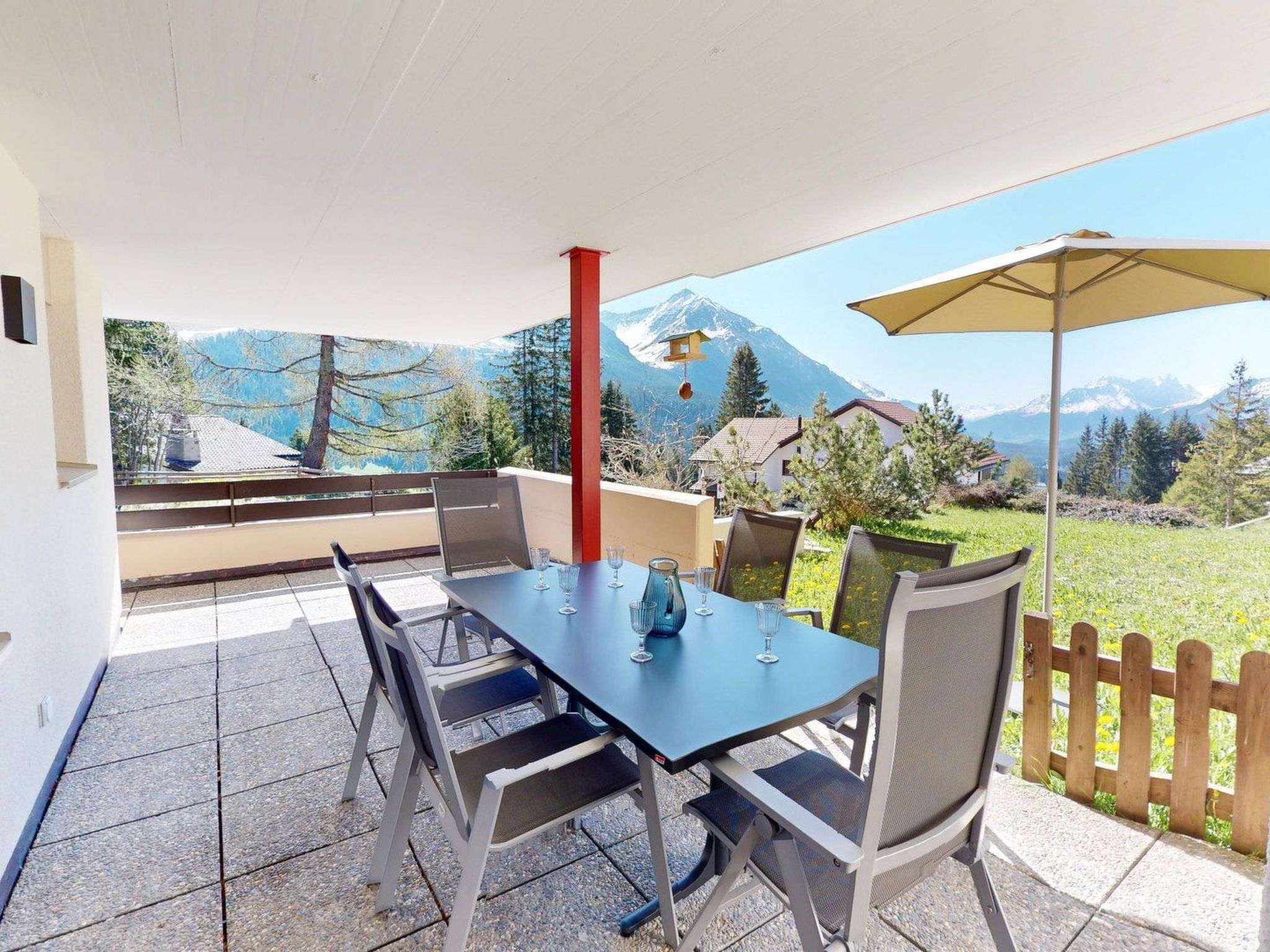 A patio with a table and chairs, a mountain view, and a wooden fence.