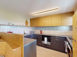 Een moderne keuken met houten kastjes, een centraal eiland en een inbouw vaatwasser.