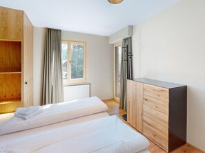 Een slaapkamer met een bed, een houten garderobe en een raam met gordijnen.