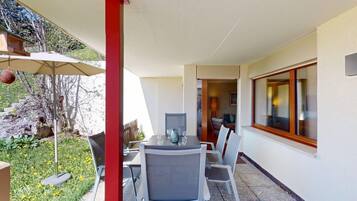 Eine Terrasse mit Tisch und Stühlen, eine rote Säule und Blick ins Innere.