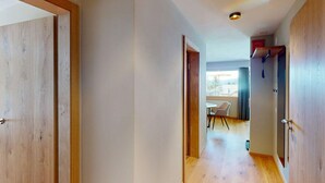 A hallway with wooden doors, a ceiling light, and a view into a dining area with a table and chairs. - 1508 Chesa Barlangia Setaria by Interhome (Valbella)
