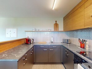 Cocina moderna con una isla central, armarios de madera y salpicadero de azulejos.