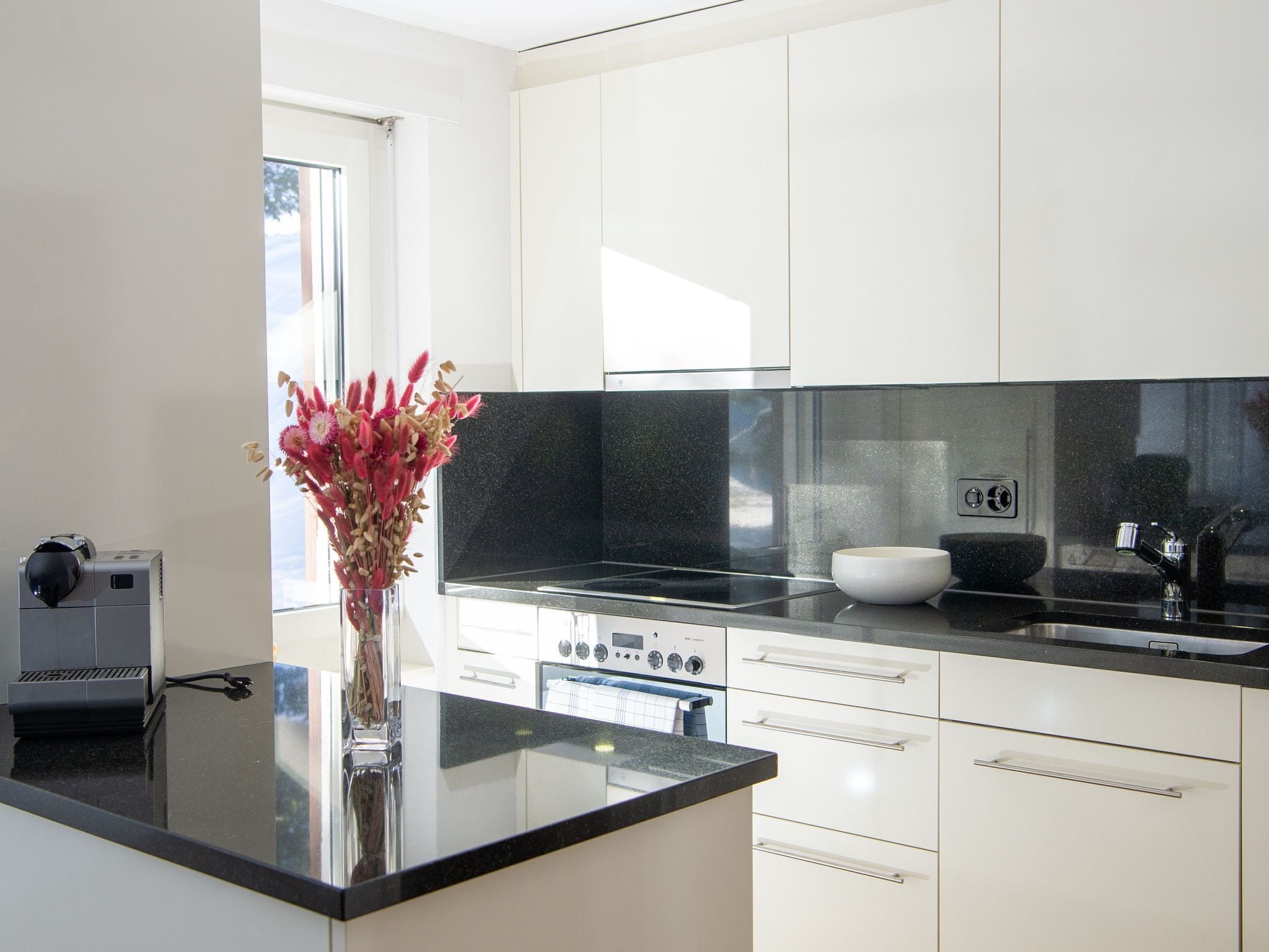 A modern kitchen with white cabinets, a black countertop, and a built-in oven.