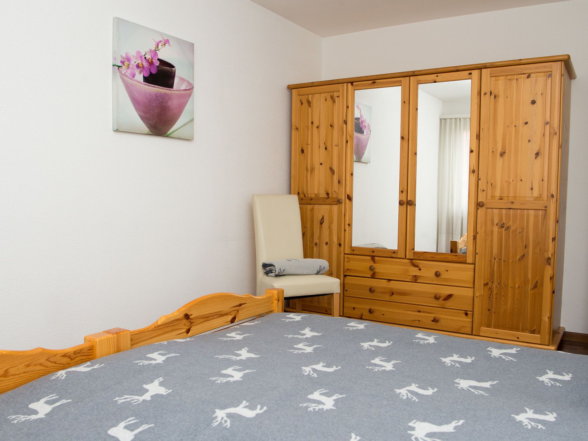 Ein Schlafzimmer mit Bett, Stuhl, Kleiderschrank und einem Bild an der Wand.
