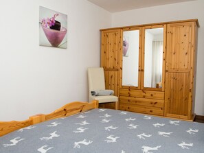 Ein Schlafzimmer mit Bett, Stuhl, Kleiderschrank und einem Bild an der Wand.