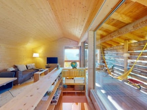 Een cabin interieur met een houten plafond, een bank, een tafel, een lamp, een televisie en een raam.