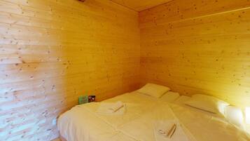 Ein Zimmer mit Holzwänden und einem Bett mit weißer Bettwäsche.