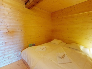 A room with wooden walls and a bed with white bedding.