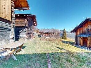 Un bâtiment rustique en bois, avec un banc en bois en premier plan.