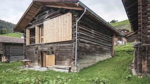 A rustic wooden cabin with a sloped roof, a wooden door, and a small porch area.
