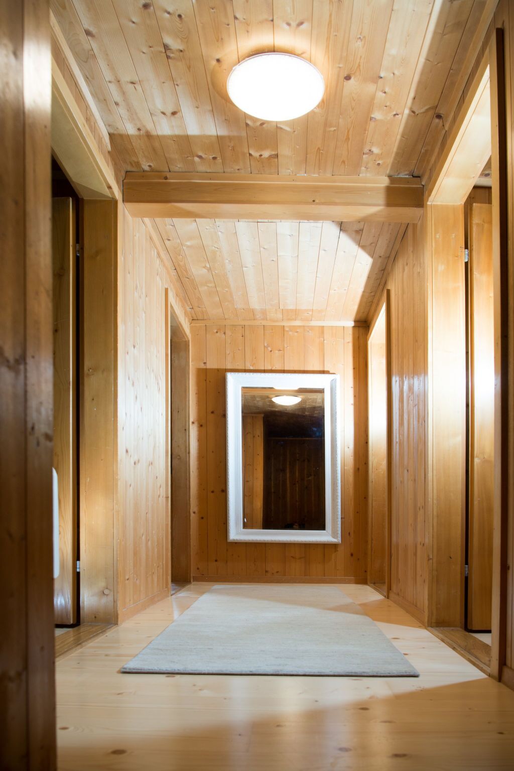 A wooden hallway with a central rectangular window and a ceiling light.