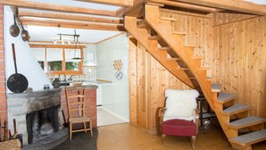 A rustic interior with a wooden staircase, a fireplace, and a kitchen area. - 1301 Haus Joch by Interhome (Churwalden)