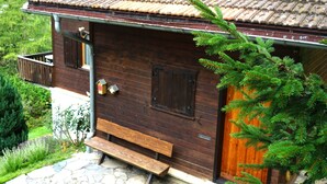 A wooden cabin with a sloped roof, a wooden door, and a bench outside. - 1301 Haus Joch by Interhome (Churwalden)