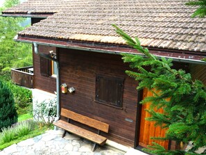 A wooden cabin with a sloped roof, a wooden door, and a bench outside. - 1301 Haus Joch by Interhome (Churwalden)
