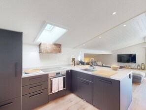 A modern kitchen with a skylight, built-in appliances, and a large island. - Apartment  by Interhome (Valbella)